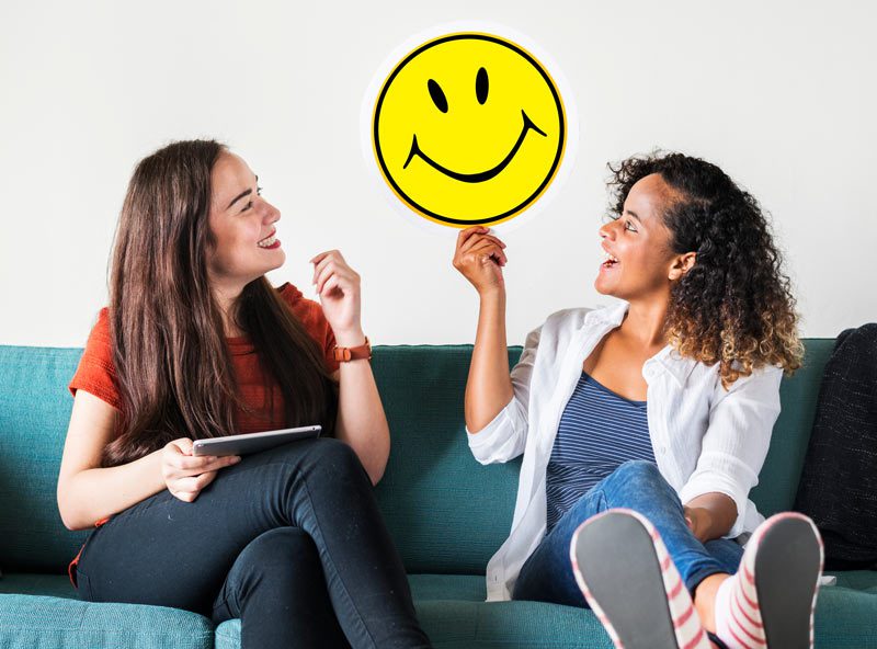 two woman holding up smiley face